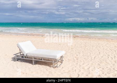 Lettino da sole bianco sorge su una spiaggia di sabbia in una giornata di sole, Repubblica Dominicana, spiaggia di Bavaro Foto Stock