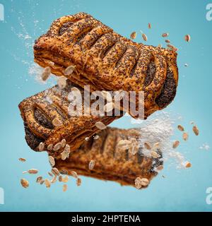 La pasta sfoglia con semi di papavero vola in aria. Cucina creativa per la colazione. Foto Stock