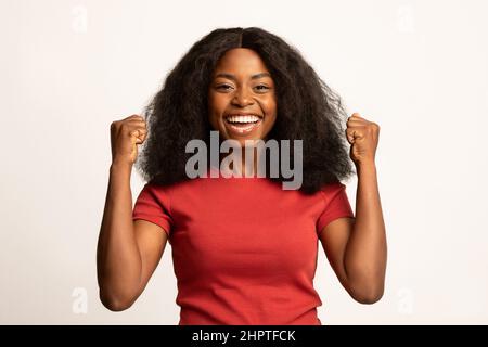 Grande successo. Ritratto di giovane donna nera gioiosa che alza i Fists con l'eccitazione Foto Stock