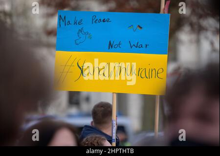 Amburgo, Germania. 23rd Feb 2022. I dimostranti mostrano una targhetta con la scritta "Make Peace not War #StandWithUkraine". Secondo la polizia, mercoledì ad Amburgo circa 200 persone si sono riunite di fronte al Consolato Generale russo per un raduno di solidarietà con l'Ucraina. Le organizzazioni giovanili di Amburgo del DOCUP, dei Verdi, della CDU e del FDP avevano chiesto il rally. Credit: Jonas Walzberg/dpa/Alamy Live News Foto Stock