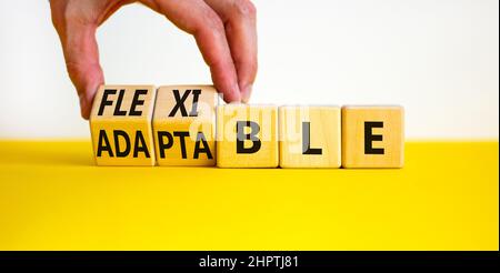 Simbolo adattabile o flessibile. L'uomo d'affari trasforma i cubi di legno e cambia la parola adattabile a flessibile. Bella tabella gialla sfondo bianco, copia Foto Stock