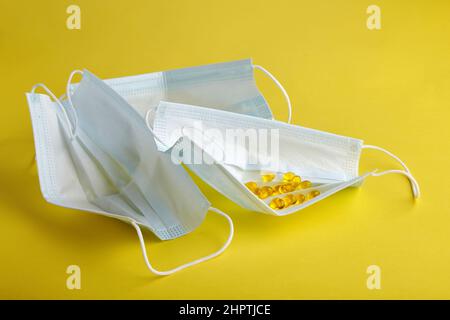 Maschere e pillole mediche su sfondo giallo Foto Stock