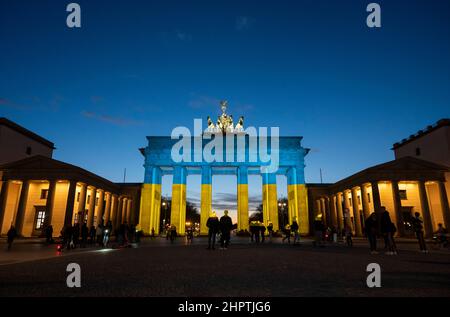 Berlino, Germania. 23rd Feb 2022. La porta di Brandeburgo è illuminata nei colori della bandiera Ucraina. Credit: Christophe Gateau/dpa/Alamy Live News Foto Stock