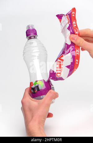 Rimozione dell'etichetta per il riciclaggio su una bottiglia di plastica Vimto monouso fotografata su sfondo bianco. Foto Stock