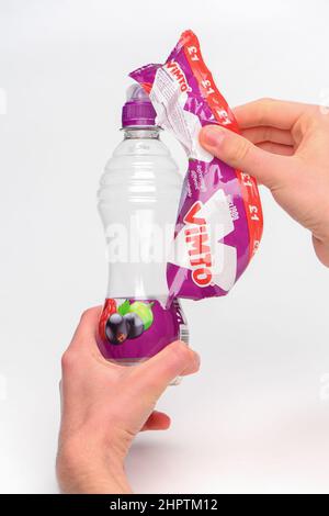 Rimozione dell'etichetta per il riciclaggio su una bottiglia di plastica Vimto monouso fotografata su sfondo bianco. Foto Stock