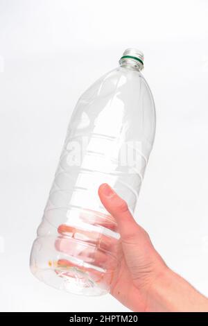 Mano che tiene una bottiglia di plastica per bevande monouso pronta per il riciclaggio fotografata su sfondo bianco. Foto Stock