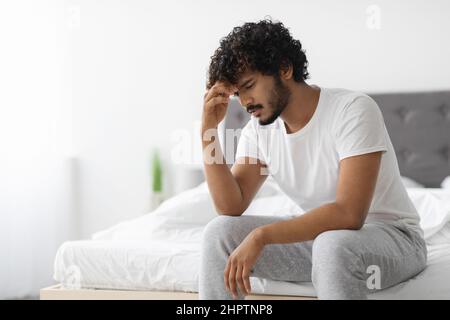 Il tipo indiano frustrato in pigiama seduti a letto Foto Stock