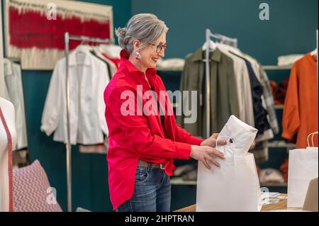 Donna che mette i vestiti nella confezione lateralmente alla macchina fotografica Foto Stock