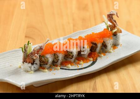 Cibo giapponese delizioso Spider Maki Roll in un piatto bianco isolato su tavolo di legno vista sul piano Foto Stock