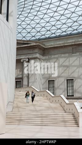 Grande scala sotto la cupola della Grande Corte: La Grande Corte al British Museum ora uno spazio interno luminoso grazie ad una massiccia cupola parziale che racchiude lo spazio. Due donne camminano giù gli stpes dal primo livello. Foto Stock