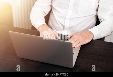 Businessman lavora al computer portatile alla scrivania dell'ufficio, digitando, navigando online. Foto Stock