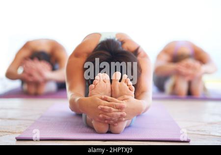Allungando le gambe e le spalle. Giovane istruttore di yoga che conduce una lezione di stretching. Foto Stock