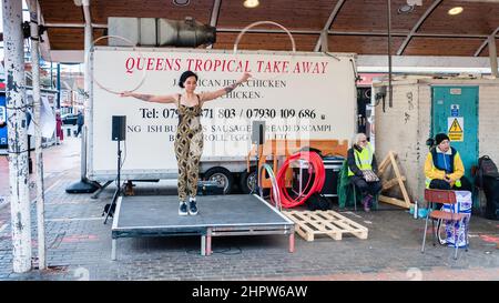 Una donna hola si libra e balla al Queens Market, Londra Foto Stock