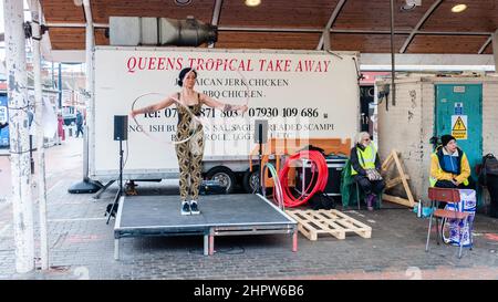 Una donna hola si libra e balla al Queens Market, Londra Foto Stock