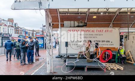 Una donna hola si libra e balla al Queens Market, Londra Foto Stock