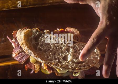 Sandwich di pastrami su una tavoletta di legno con delizioso incontro sul pane baguette con formaggio, spazio copia in parti dell'immagine. Foto Stock