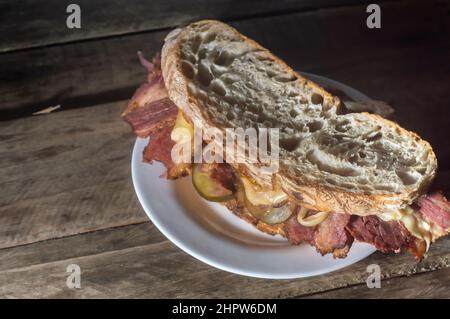 Sandwich di pastrami su una tavoletta di legno con delizioso incontro sul pane baguette con formaggio, spazio copia in parti dell'immagine. Foto Stock