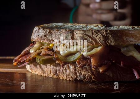 Sandwich di pastrami su una tavoletta di legno con delizioso incontro sul pane baguette con formaggio, spazio copia in parti dell'immagine. Foto Stock