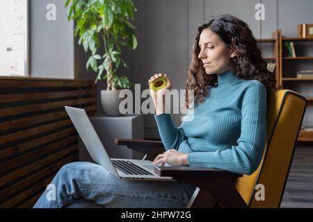 Giovane dipendente femminile soddisfatto che stringe l'espansore carpale in mano e guarda lo schermo del laptop Foto Stock