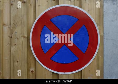 Cartello stradale rosso e blu "No stopping" avvitato su una recinzione di legno accanto ad una porta di metallo (immagine orizzontale), Hildesheim, bassa Sassonia, Germania Foto Stock