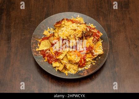 Nachos al forno croccanti con strisce di pancetta fritta e mozzarella fusa. Una combinazione semplice e spettacolare Foto Stock