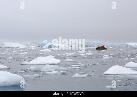 I passeggeri della crociera da le Boreal attraversano le acque ghiacciate di Paradise Bay in una barca zodiacale, appena a est dell'Isola di Bryde, Antartide. Foto Stock