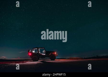 Black Jeep Wrangler parcheggiato sotto il cielo stellato notte Foto Stock