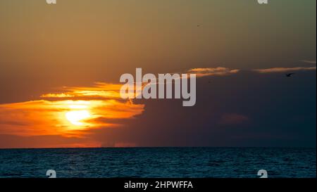 L'epico tramonto colorato illumina le nuvole sulle acque blu Foto Stock