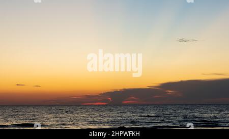Cielo epico al tramonto con raggi di luce dall'orizzonte sopra l'oceano Foto Stock