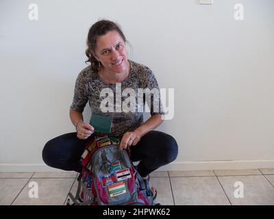 Donna che si prepara al viaggio. Lei sta imballando il suo passaporto nel suo zaino che è coperto con bandiere di diversi paesi Foto Stock