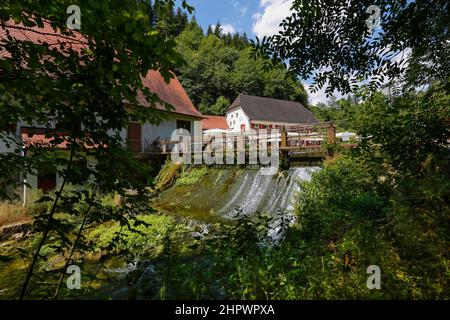 Mulino di Wimsen sul corso del fiume Ach, Bannmuehle, stramazzo, nel retro Gasthof Friedrichshoehle, Hayingen-Wimsen, Baden-Wuerttemberg, Germania Foto Stock