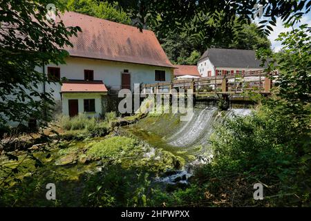 Mulino di Wimsen sul corso del fiume Ach, Bannmuehle, stramazzo, nel retro Gasthof Friedrichshoehle, Hayingen-Wimsen, Baden-Wuerttemberg, Germania Foto Stock