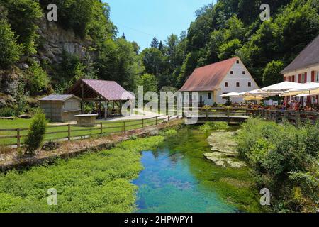 Mulino Wimsen sul corso del fiume Ach, Bannmuehle, sul giardino ristorante a destra con ombrelloni, gente, Hayingen-Wimsen Foto Stock