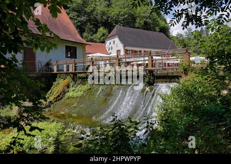 Mulino di Wimsen sul corso del fiume Ach, Bannmuehle, stramazzo, nel retro Gasthof Friedrichshoehle, Hayingen-Wimsen, Baden-Wuerttemberg, Germania Foto Stock