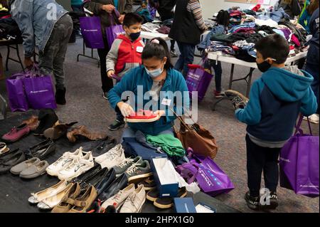 Marietta, Georgia, Stati Uniti. 13th Feb 2022. Una madre esamina le scarpe per se stessa e i suoi figli di famiglia da pile di abiti donati alla First Baptist Church di Marietta, Georgia, durante una cena per individui o famiglie che stanno lottando finanziariamente o senzatetto. (Credit Image: © Robin Rayne/ZUMA Press Wire) Foto Stock