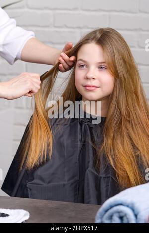 Parrucchiere che fa un capello a ragazza carina in parrucchiere. Giovane ragazza al parrucchiere Foto Stock