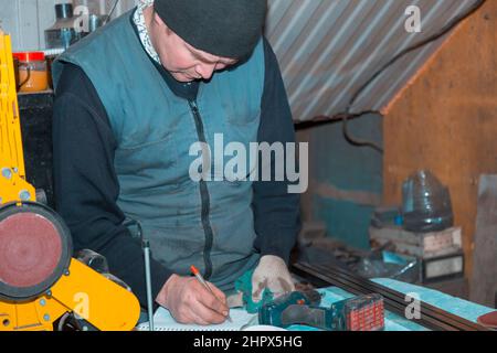 Il master della macchina di emeria di nastri scrive le informazioni in un notebook con una penna stilografica Foto Stock