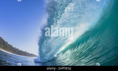 Onde oceaniche cave che precipita l'acqua di mare su una barriera corallina poco profonda con retro-luce sole primo piano nuoto foto in natura potere Foto Stock