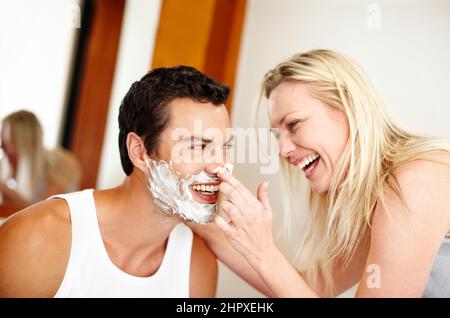 I migliori amici fanno i migliori rapporti. Scatto di una giovane donna che mette la crema da barba sul marito e ride. Foto Stock