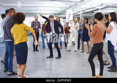 Tutto il lavoro e nessun gioco.... Sparato di un uomo d'affari in un vestito che balla in ufficio per gli imbrogli dei colleghi. Foto Stock