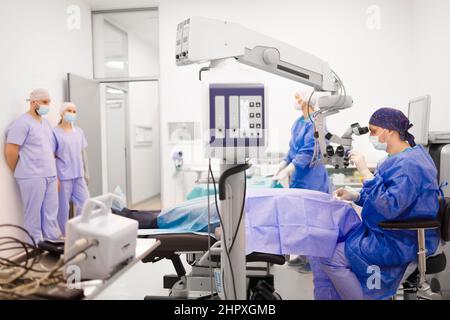 Un team di personale medico e medici che lavorano su un paziente in una sala operatoria Foto Stock