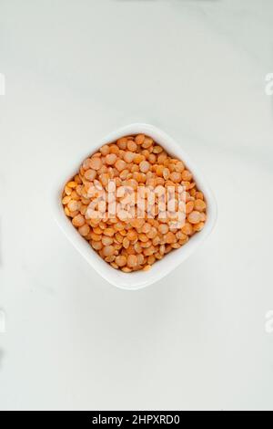 Ciotola di lenticchie rosse su sfondo di marmo bianco Foto Stock