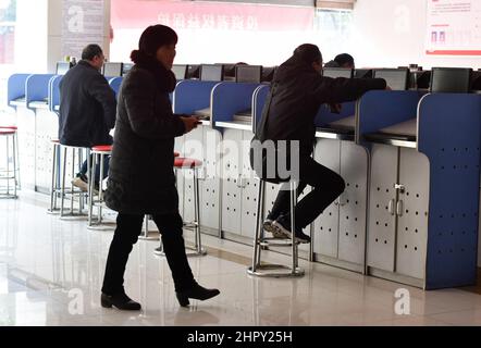 Fuyang, Cina. 24th Feb 2022. Una donna entra mentre diversi investitori guardano l'indice composito di Shanghai sui monitor. Sotto l'influenza della guerra Russia-Ucraina, il mercato cinese delle azioni A un tempo vide transazioni di panico. Il fatturato dei due mercati superava presto i trilioni di yuan, e alla fine del volume di negoziazione superava i 1,3 trilioni di yuan, un massimo di 5 mesi. Alla fine del trading, l'indice di Shanghai era a 3429 punti, in calo del 1,7%, l'indice di Shenzhen a 13252 punti, in calo del 2,2%, l'indice di gemme a 2783 punti, in calo del 2,11%. Credit: SOPA Images Limited/Alamy Live News Foto Stock