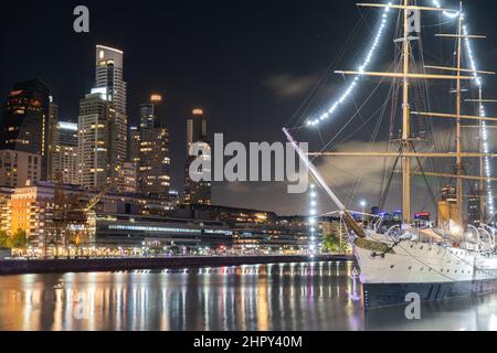 Foto notturna della vecchia barca al porto, con le luci della città a Puerto Madero, Buenos Aires, Argentina. Foto Stock