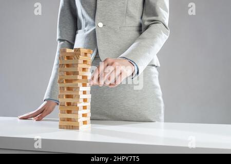 Uomo d'affari che rimuove il blocco di legno dalla torre Foto Stock