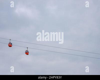 Cabine rosse di funicolare ad Antalya, Turchia sullo sfondo di nuvole di pioggia. Gita in funivia ai punti panoramici delle montagne. Durante il viaggio in funivia i turisti godono di splendide vedute della città e della natura Foto Stock