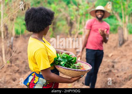 Ritratto di una bella femmina contadina africana che porta cesto di verdure Foto Stock