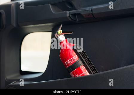 Estintore rosso in una porta nera del carrello. Foto Stock