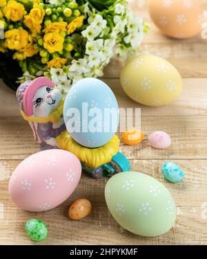 Uova di pasqua colorate, caramelle e fiori su un rustico tavolo di legno Foto Stock