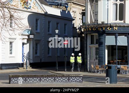 Due uomini in giacche ad alta visibilità che camminano attraverso Trinity Square, Hull, Humberside, East Yorkshire, Inghilterra Regno Unito Foto Stock